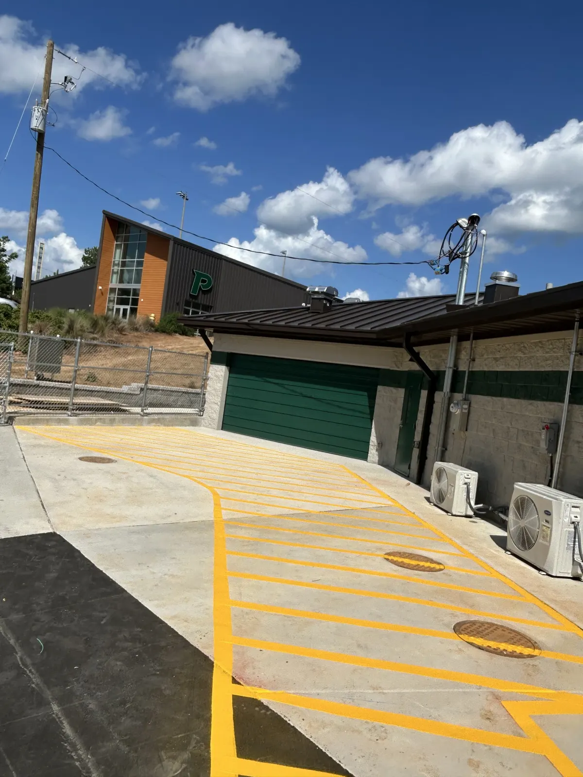 Bright yellow hatched safety zone painted by BAR Striping at a facility entrance