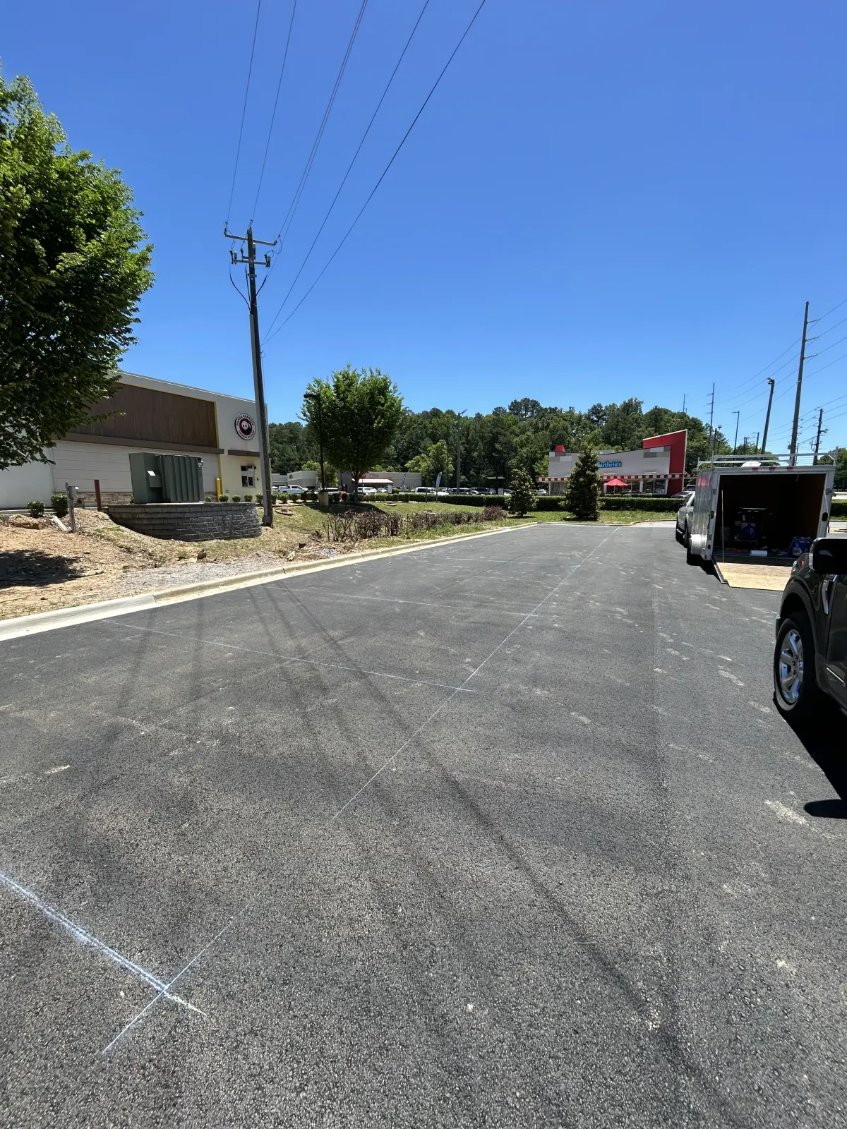 Same retail parking lot before striping — blank asphalt